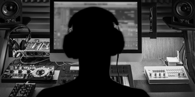 Foto em preto e branco mostrando de costas um profissional de eventos controlando mesa de som em um evento.